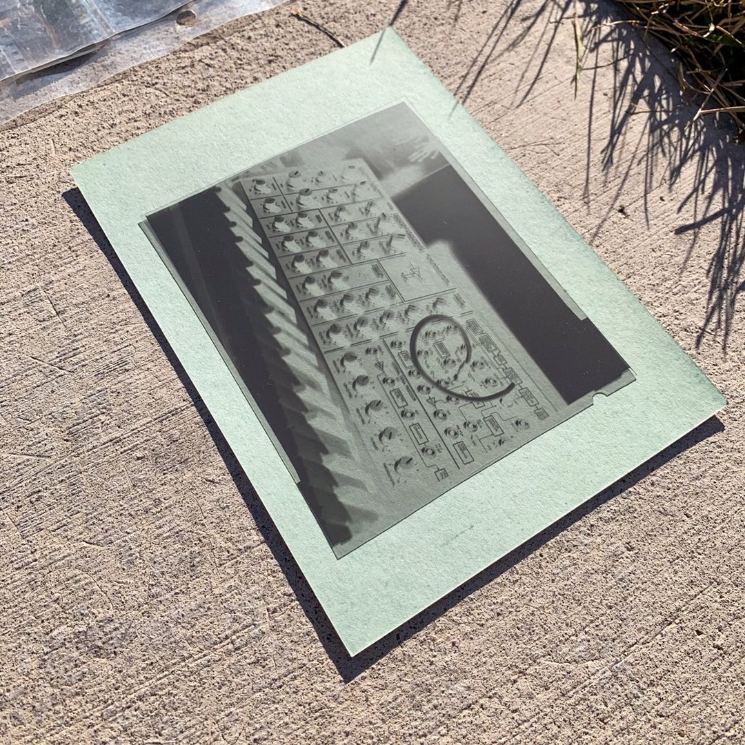 Cyanotype paper on ground with 4x5 negative depicting an analog synthesizer on top of it