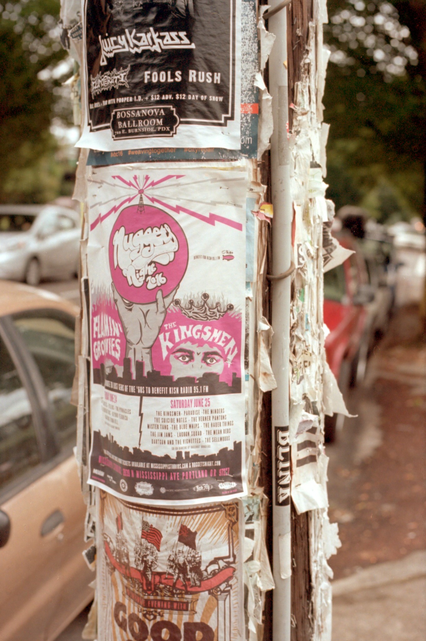 Photograph of a pole on a street covered in band fliers